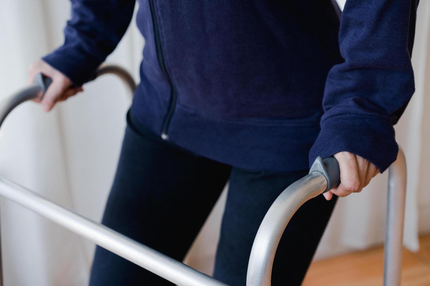 Cropped view of elderly man walking with frame at home, closeup. young male asian using medical equipment to move around his house. Disabled older person in need of professional help photo