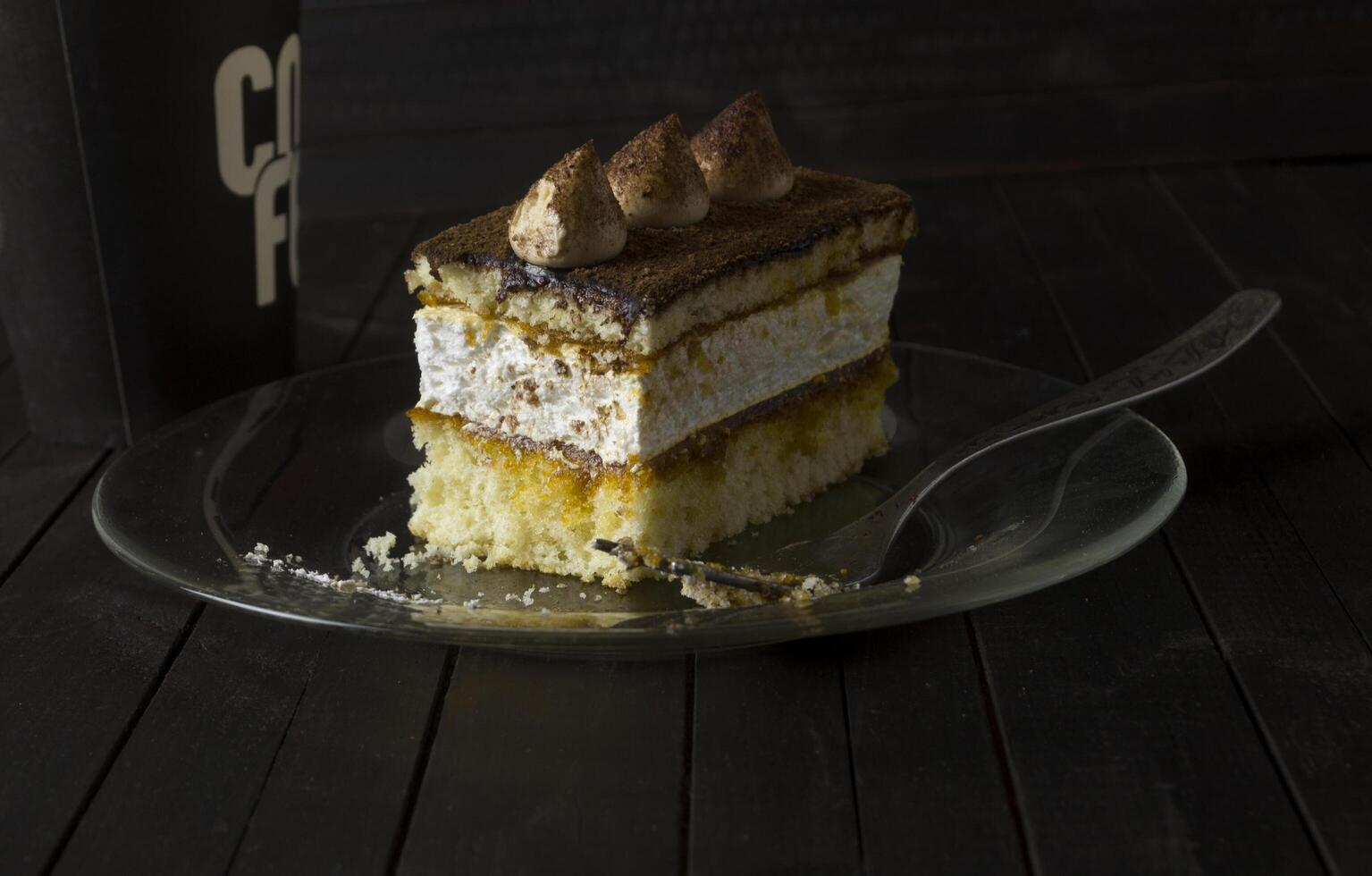 Truffle cake on glass plate on dark wooden table. photo