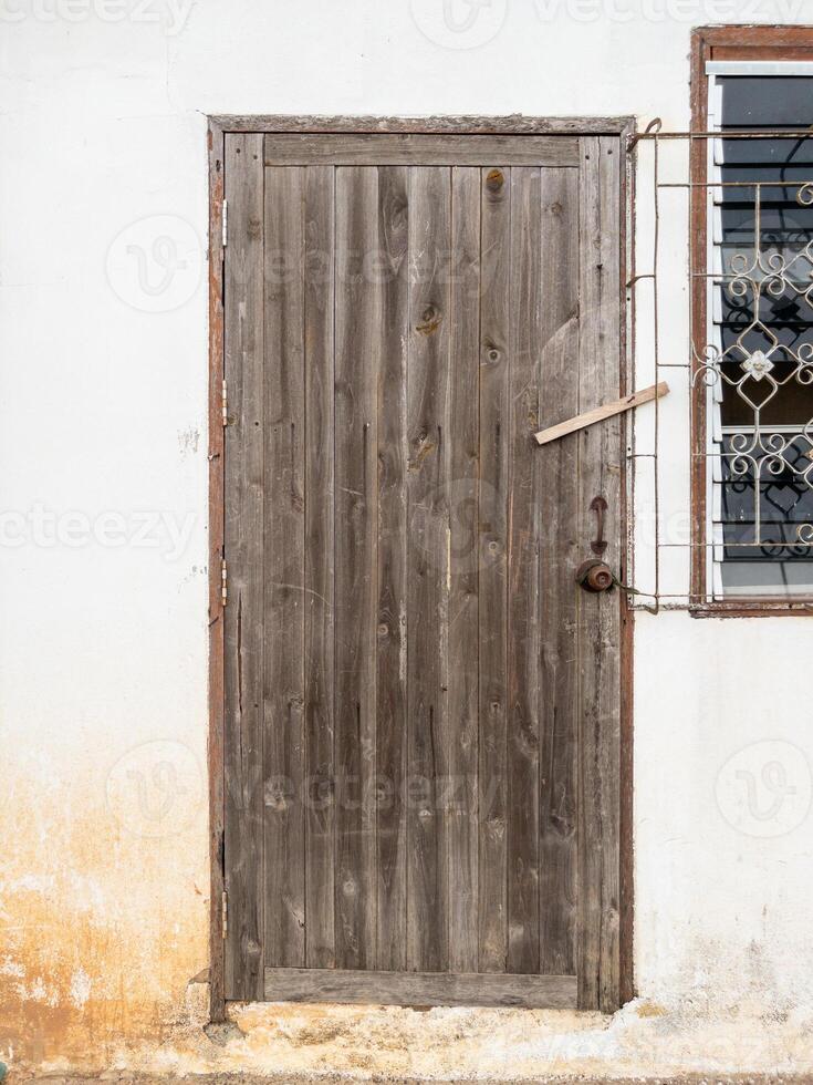 The old wooden door with the wood latch on the white wall. photo