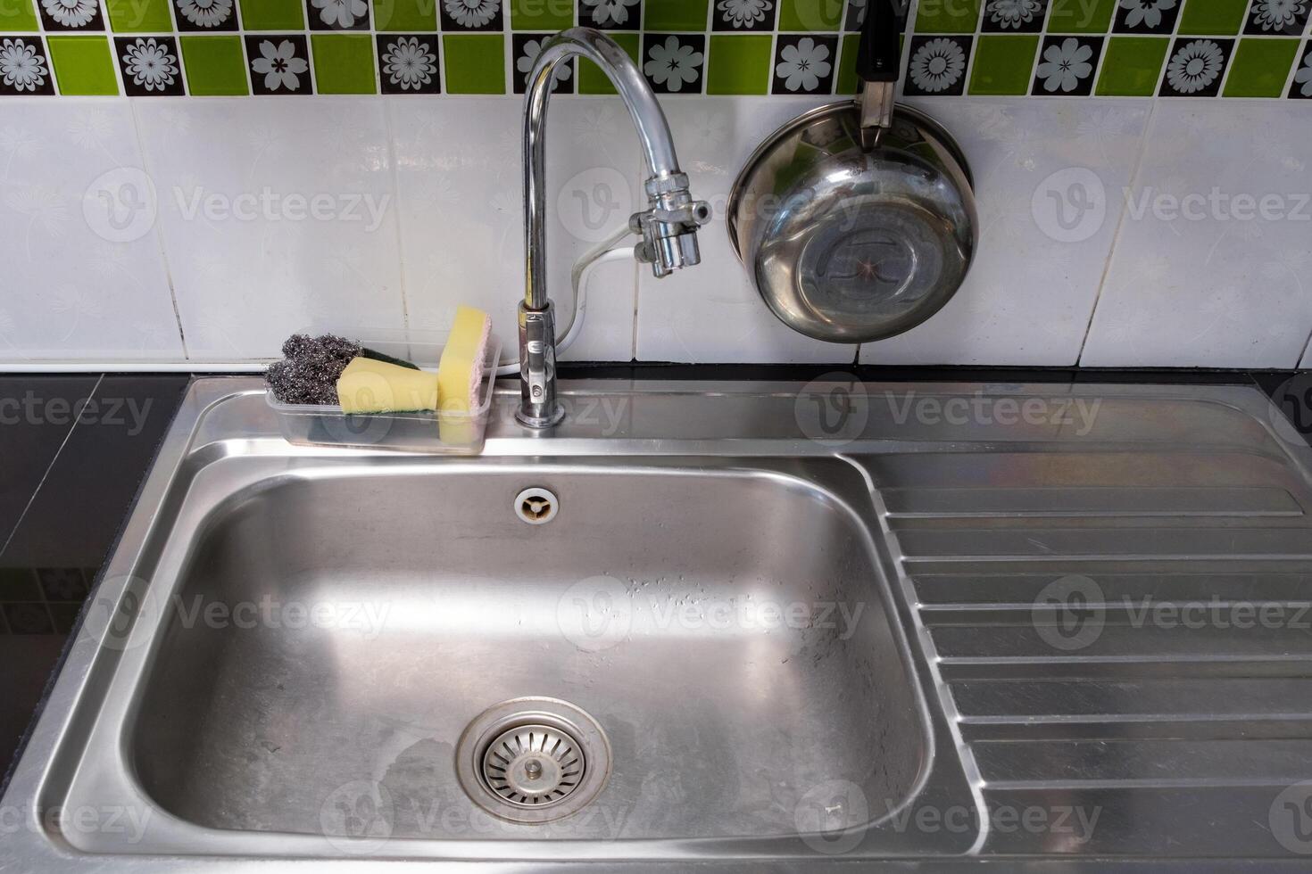 The clean metal sink with the chrome tap after washing on the modern counter. photo