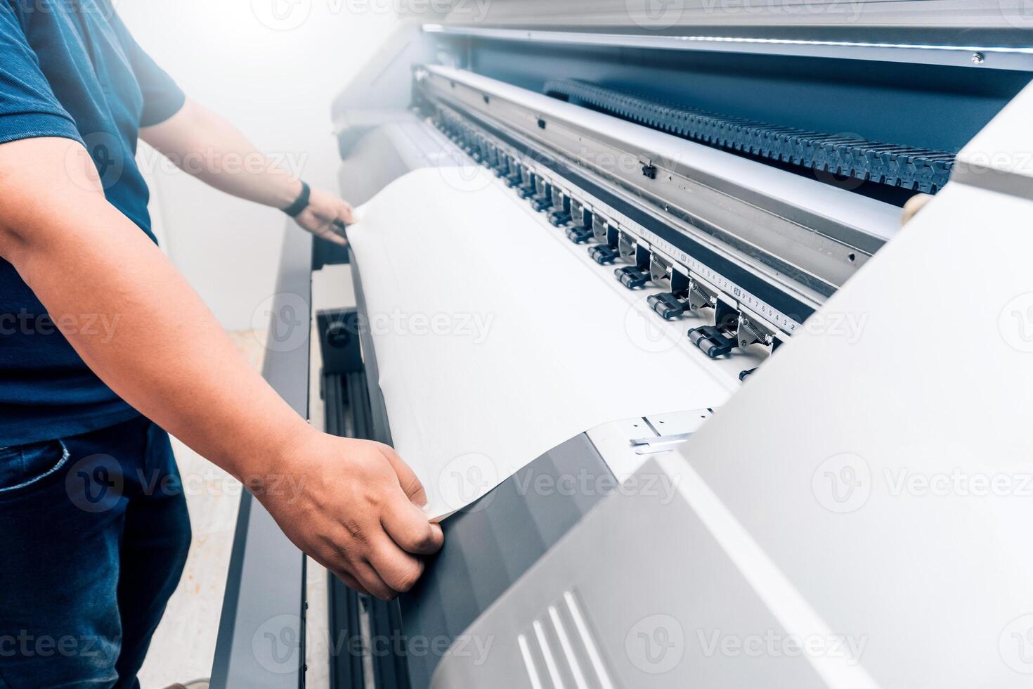 man holding printable material on alarge format printing plotter. photo