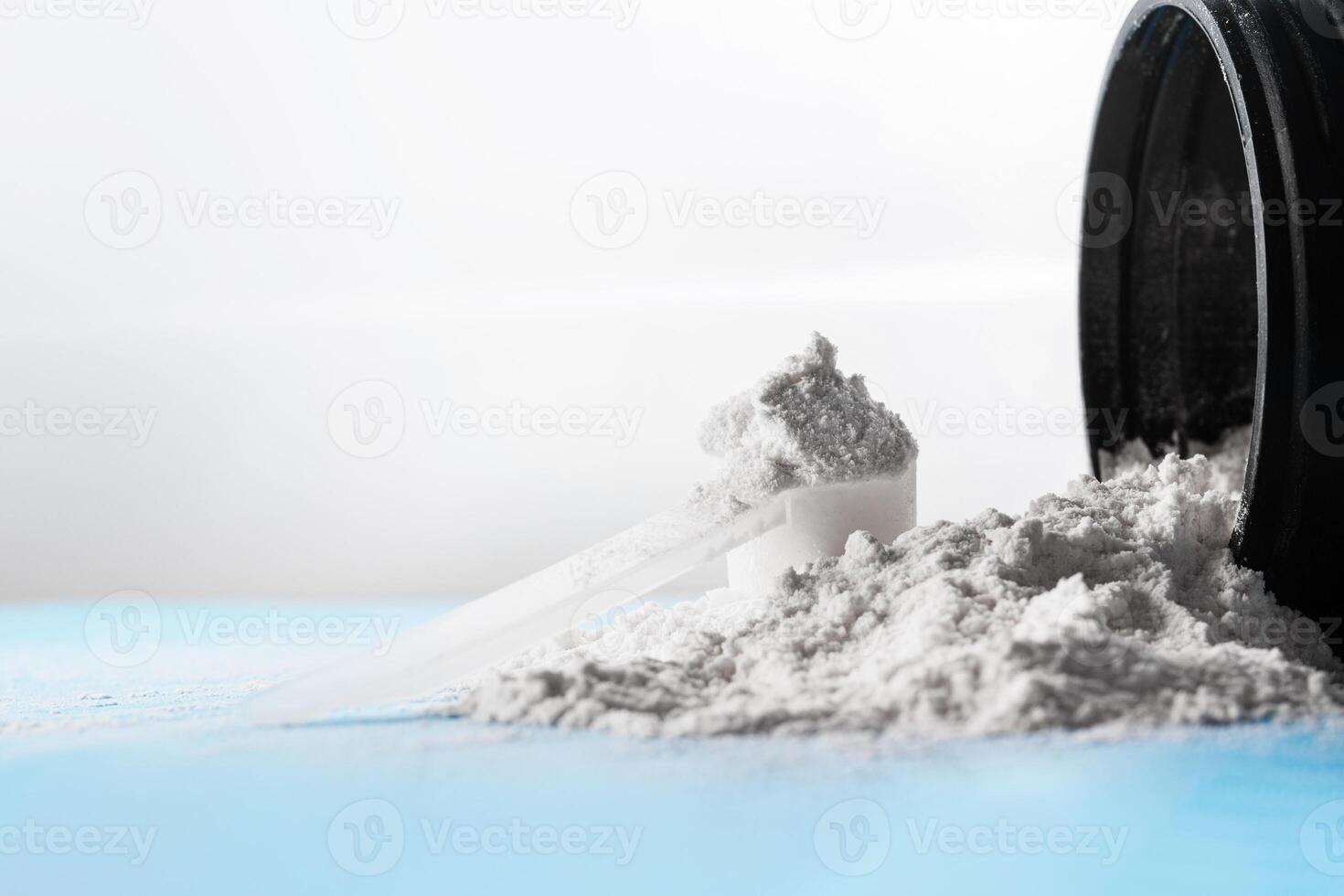 Closed up shot of a scoop of creatine powder next to a bottle. photo