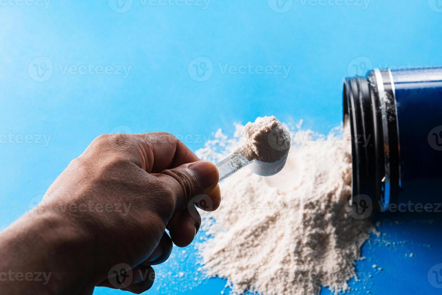 A person's hands holding a scoop full of dietary supplement powder. photo