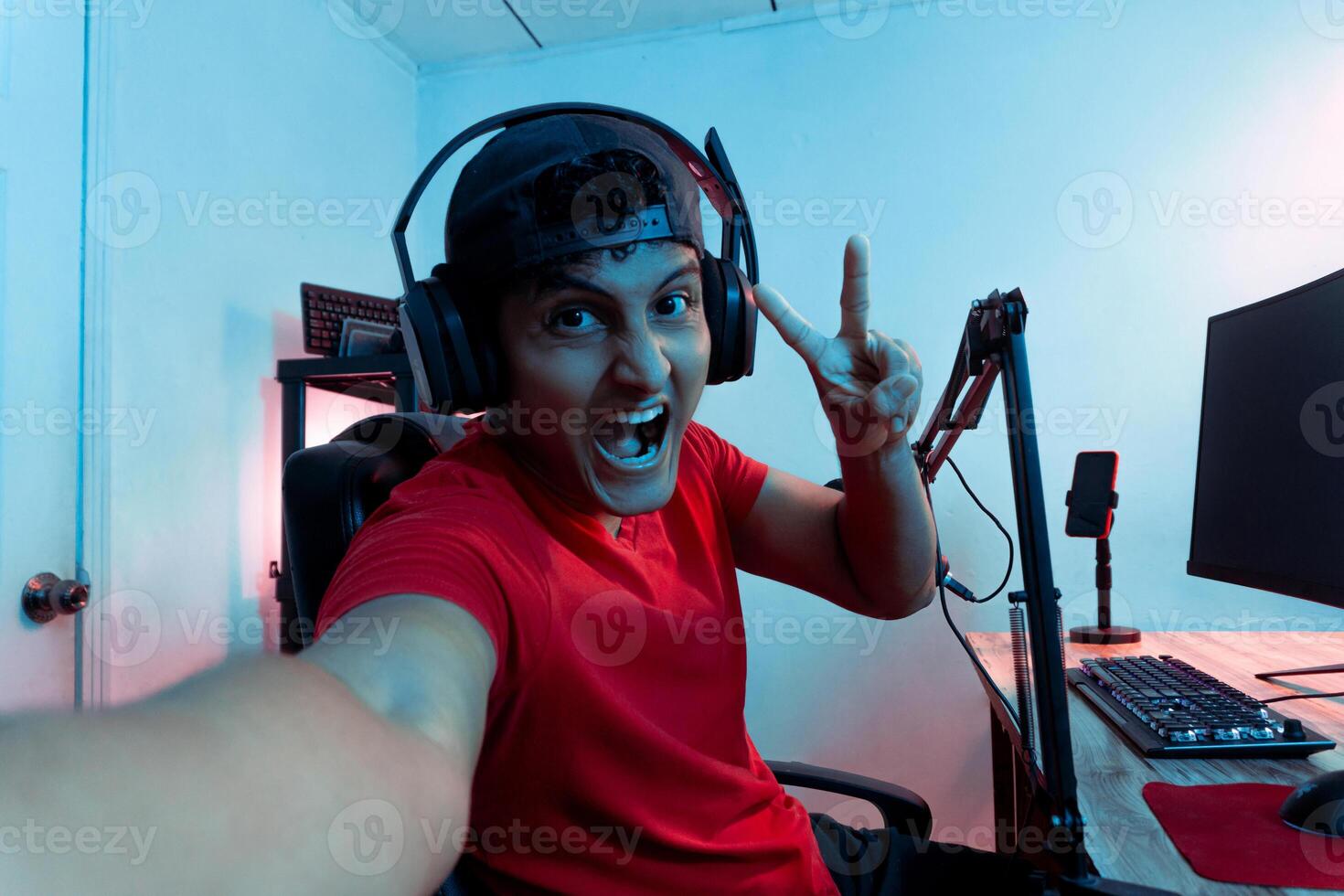 Cheerful young Hispanic man taking a selfie inside a video game room. photo