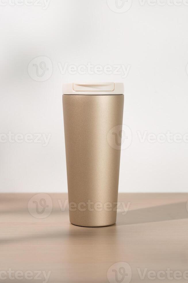 Gold stainless steel tumbler on a wooden table. photo