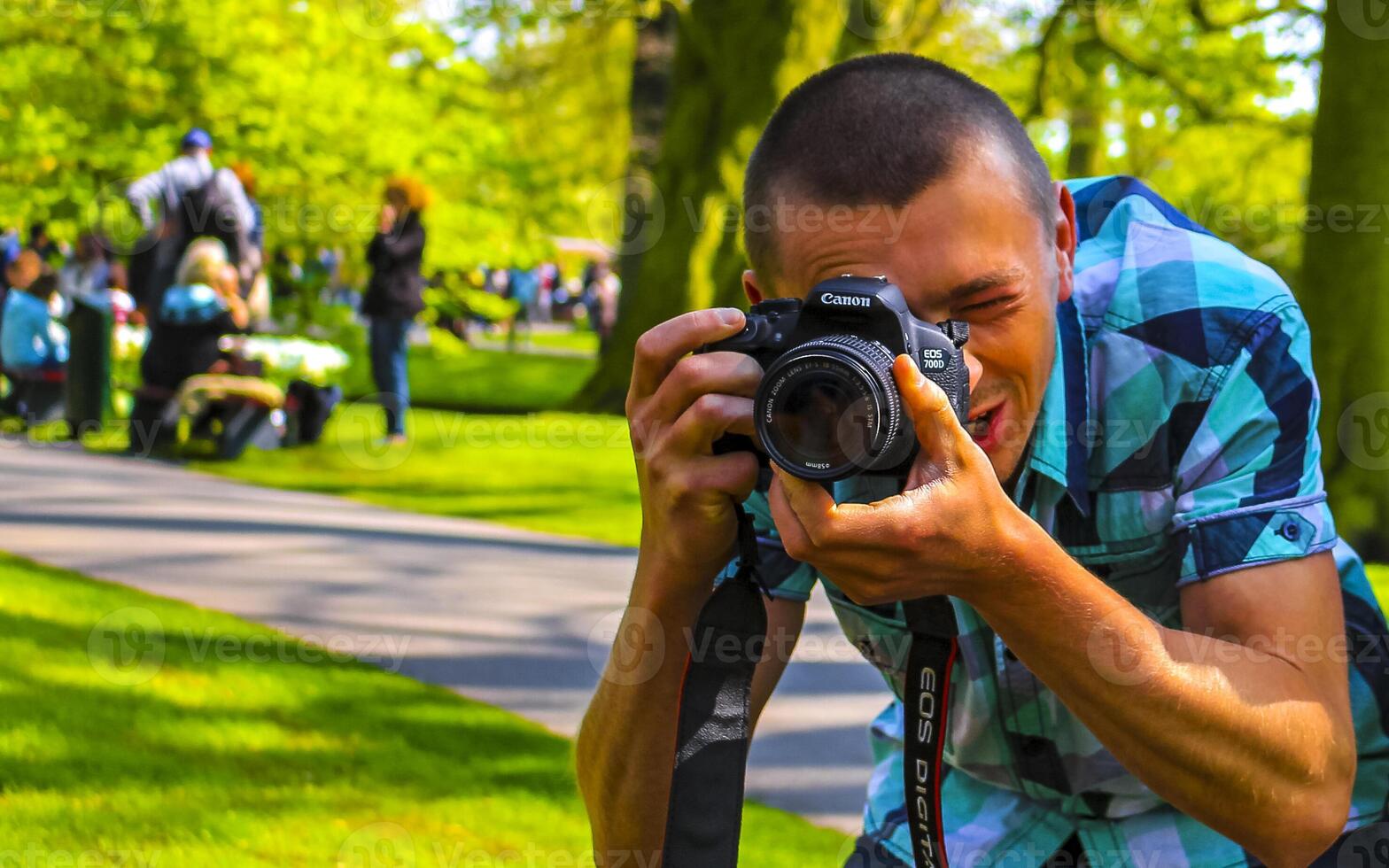 Man tourist takes photo tulip flowers park in Lisse Netherlands.