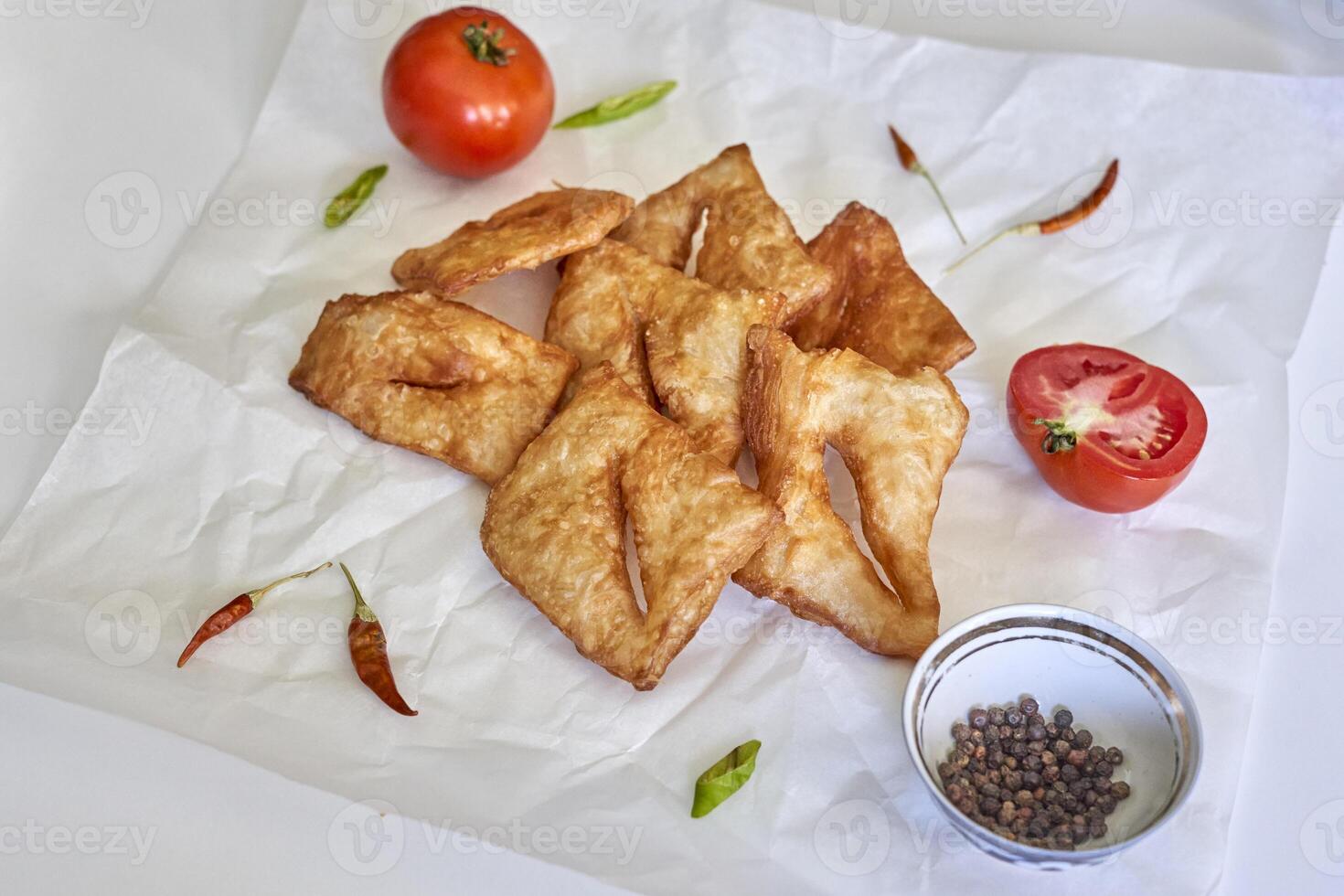 fried pastry on paper with tomatoes and spices photo