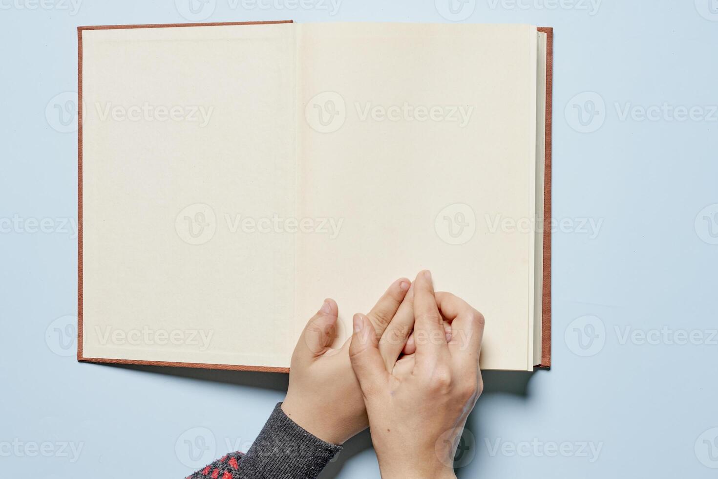 storybook concept with child's hand holding open book on blue background photo