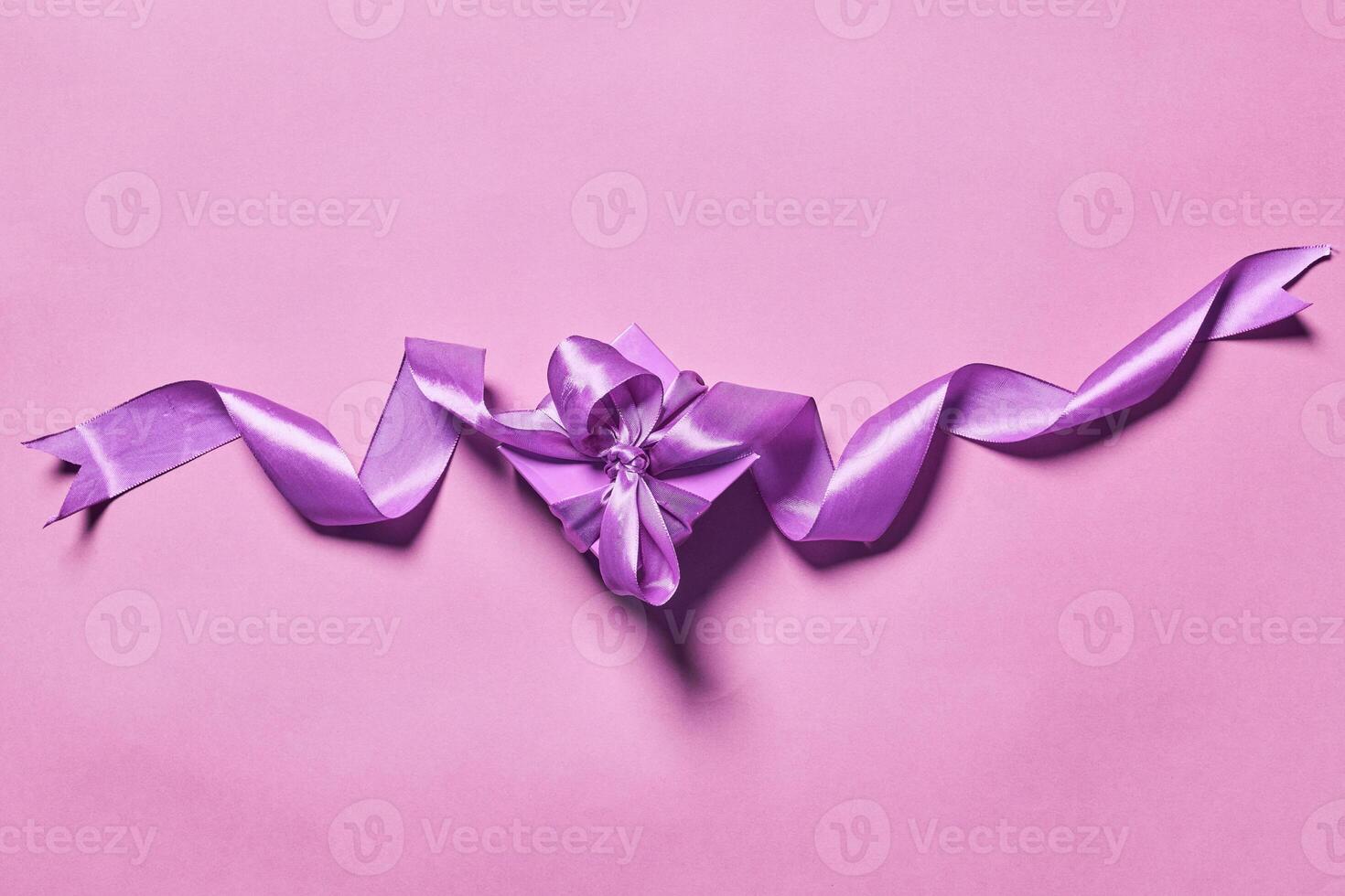 purple ribbon and gift wrapped on pink background photo