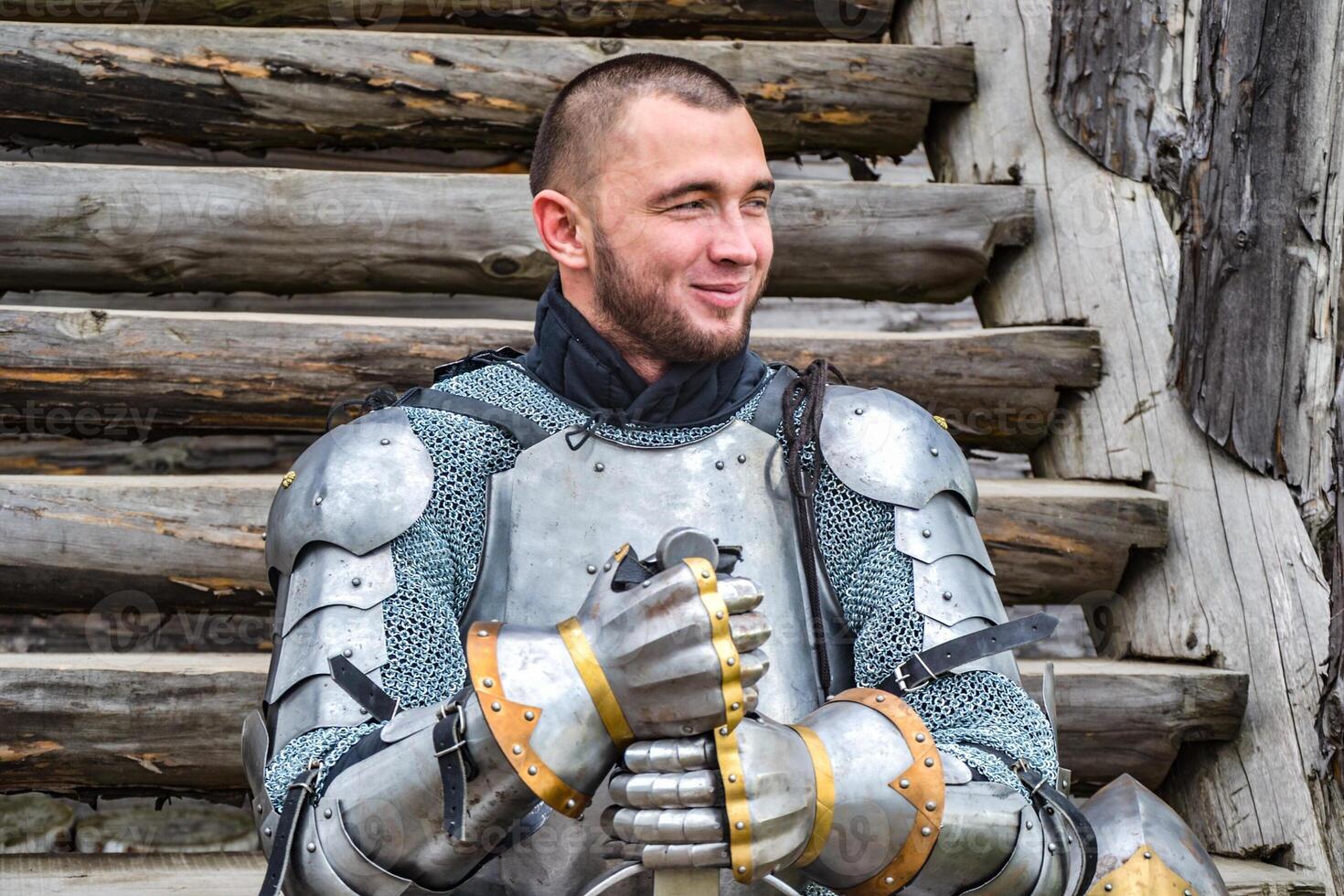 Knight in the armor on the wooden steps. Knightly armor and weapon photo