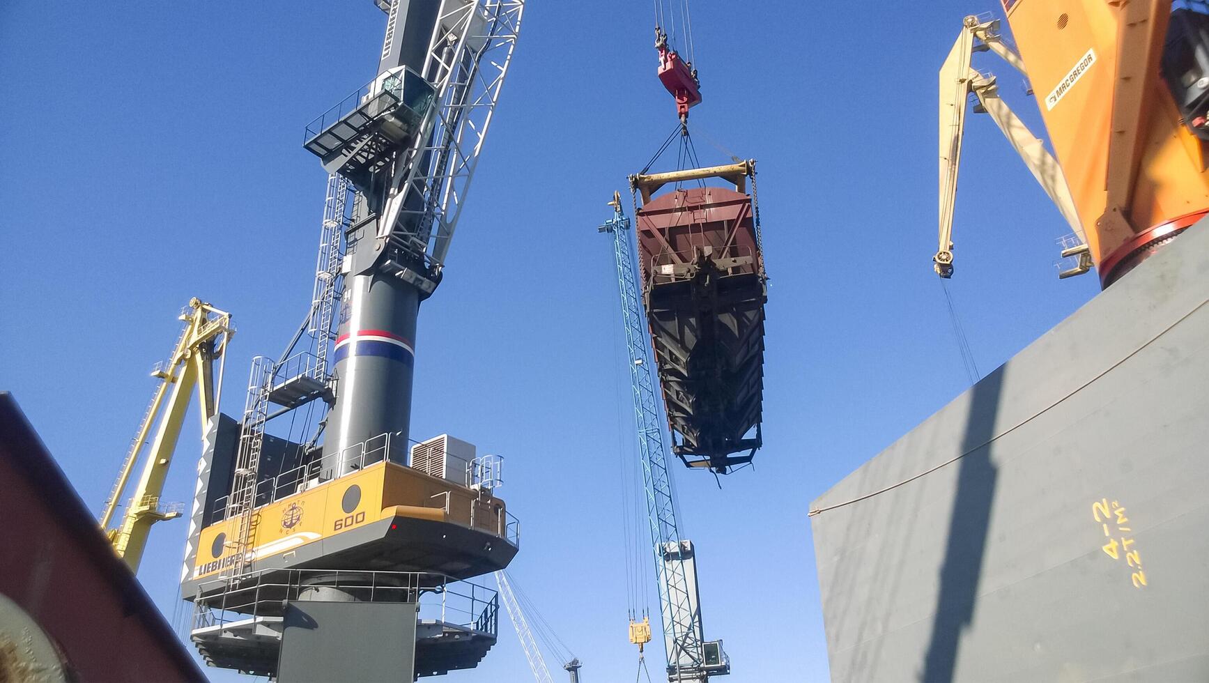 Russia, Novorossiysk 2021. Moving freight railway car in the port by a port crane. Cargo lifting operations. Industrial port photo