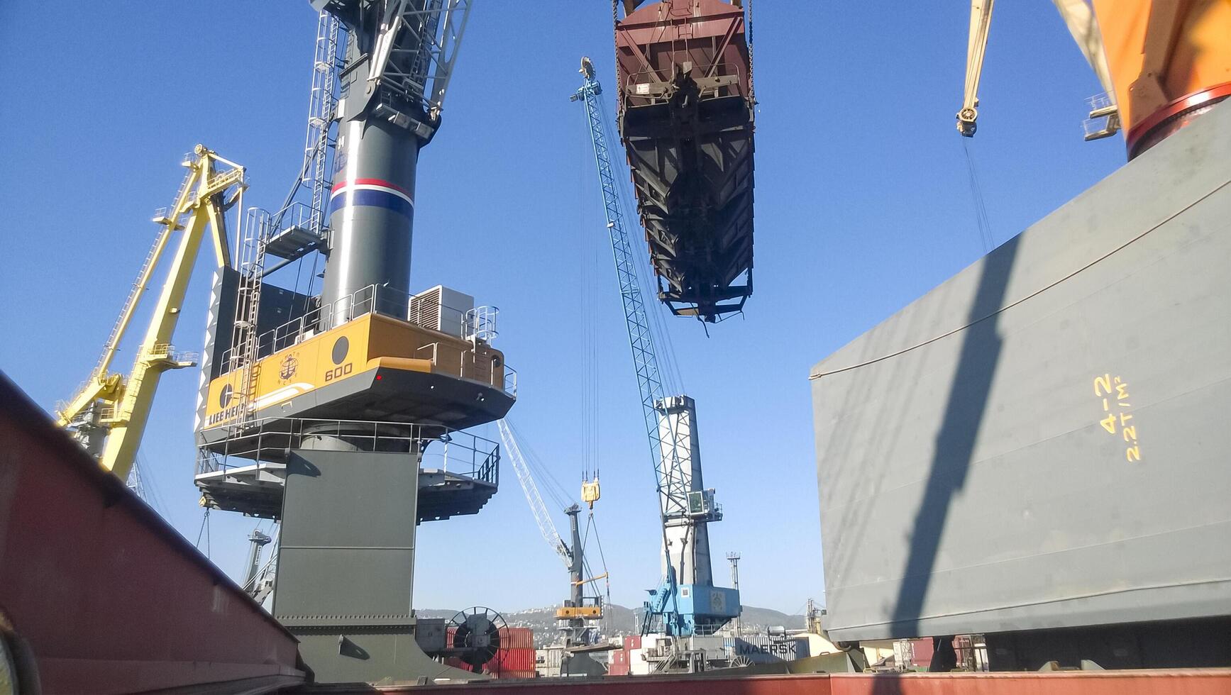 Russia, Novorossiysk 2021. Moving freight railway car in the port by a port crane. Cargo lifting operations. Industrial port photo