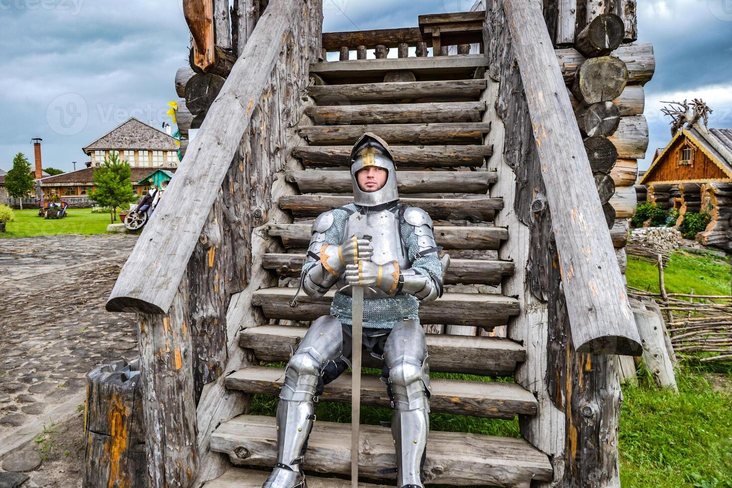 Knight in the armor on the wooden steps. Knightly armor and weapon photo