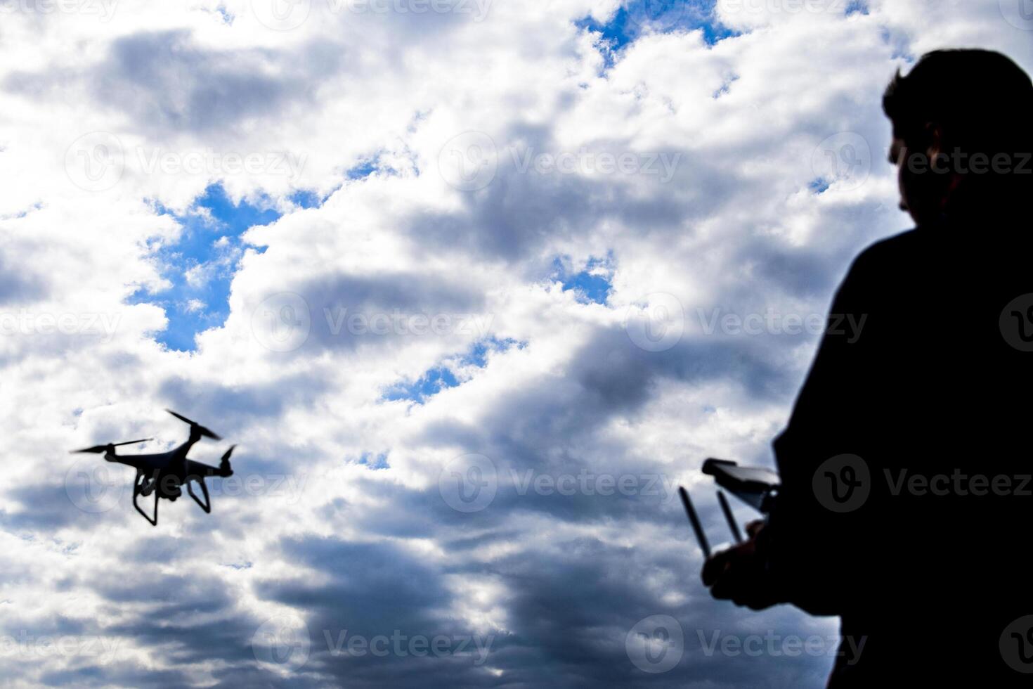 A man with a remote control in his hands. Controlling the flight of the drone against the sky. Phantom. photo