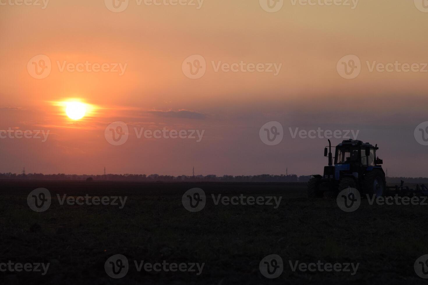 Tractor plowing plow the field on a background sunset. tractor silhouette on sunset background photo