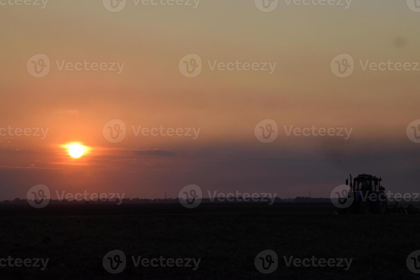 Tractor plowing plow the field on a background sunset. tractor silhouette on sunset background photo