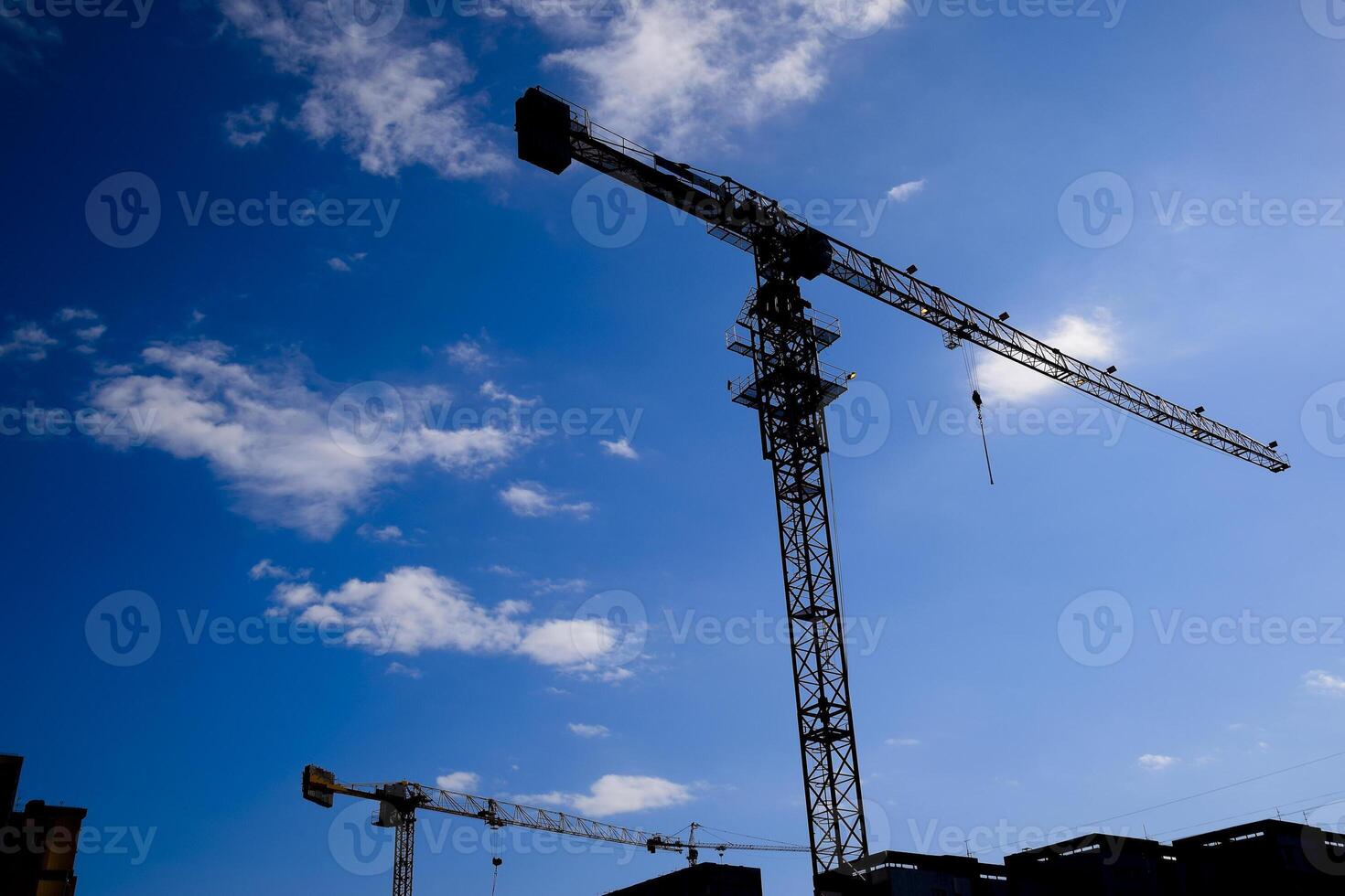 Tower building crane against the blue sky and sun. Construction of new buildings with a crane. Tower crane photo