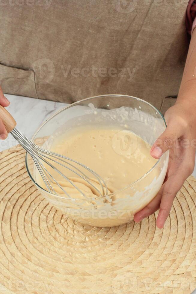 Woman Hand Mixing Flour Batter in Transparent Bowl photo