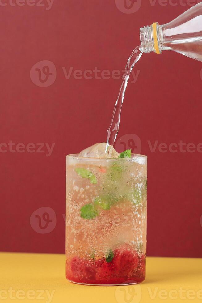 verter soda espumoso agua a el vaso con fresa mojito foto