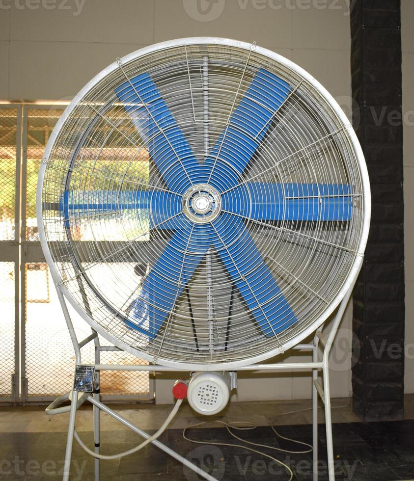 a large fan with blue blades on a floor photo