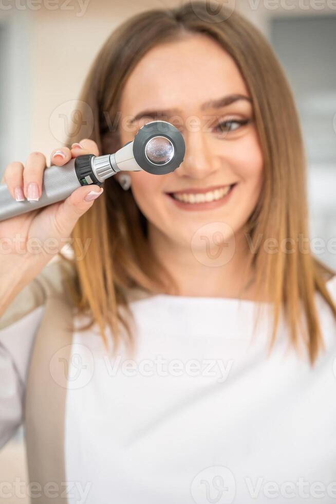 Portrait of young specialist dermatologist with dermatoscope in uniform and gloves in doctor office before examination in clinic. High quality photo