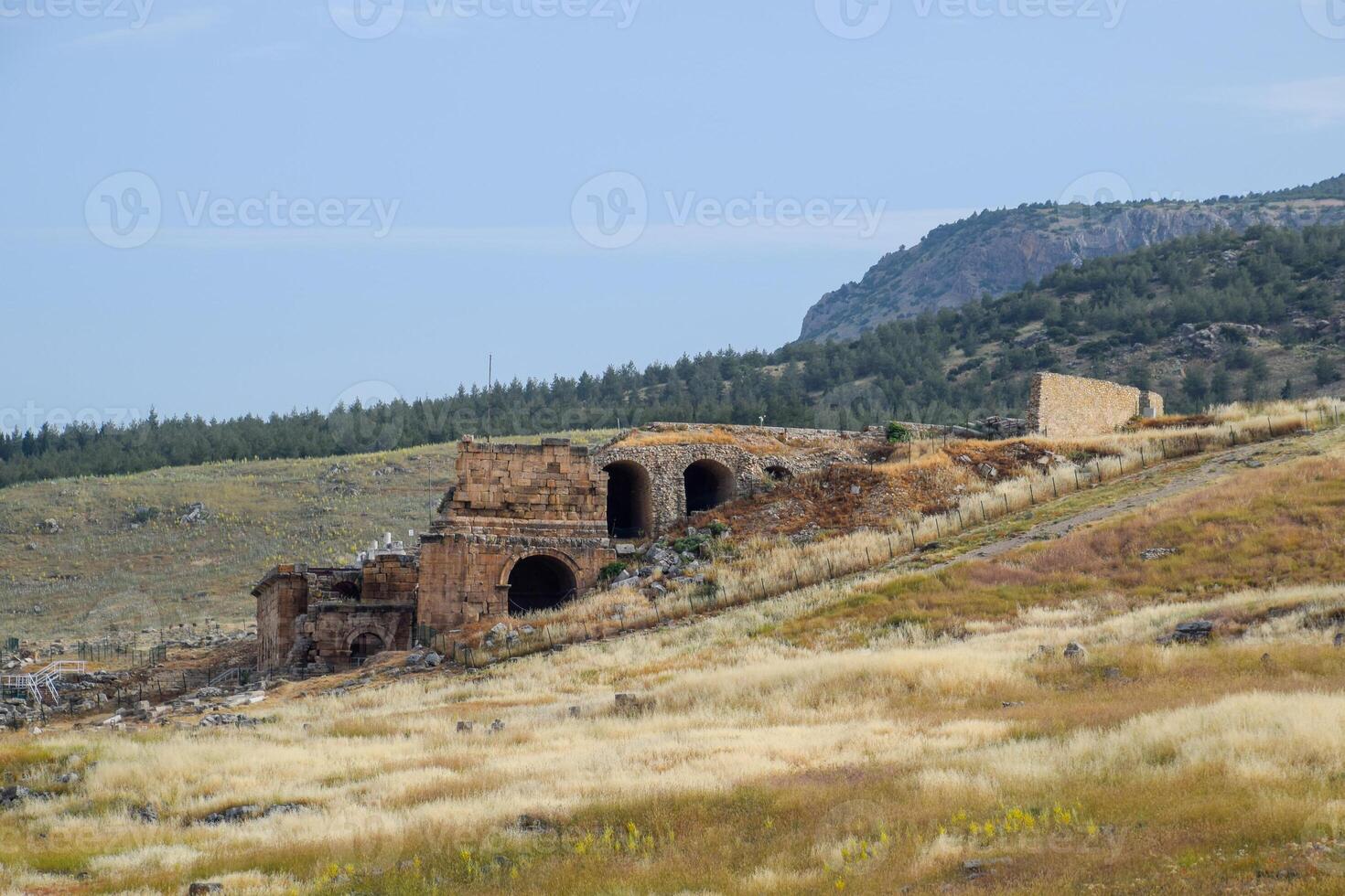 Ancient antique amphitheater in city of Hierapolis in Turkey. Side view. Steps and antique statues with columns in the amphitheater photo