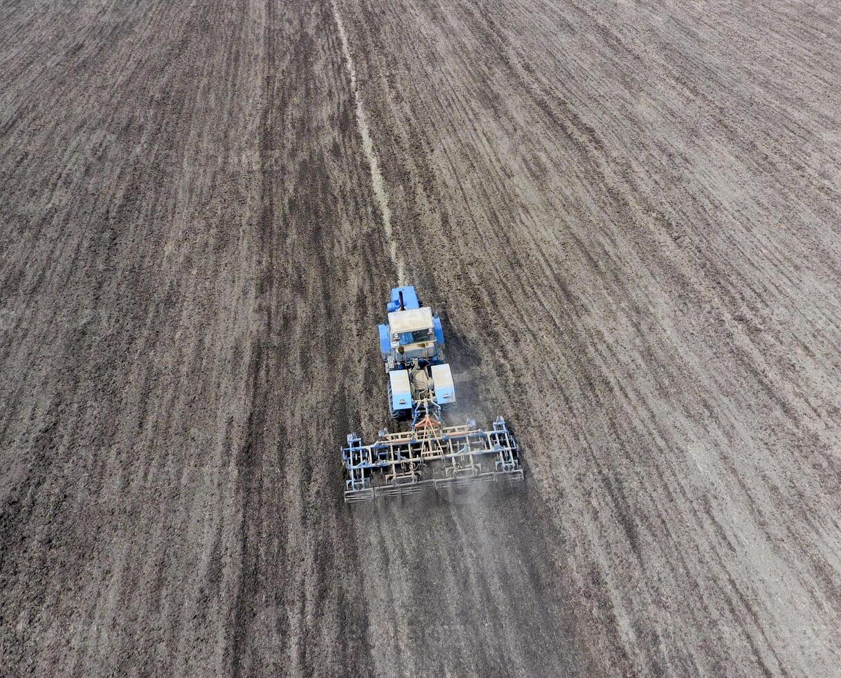 The tractor plows the field. Under sowing, the soil is loosened on the field. photo