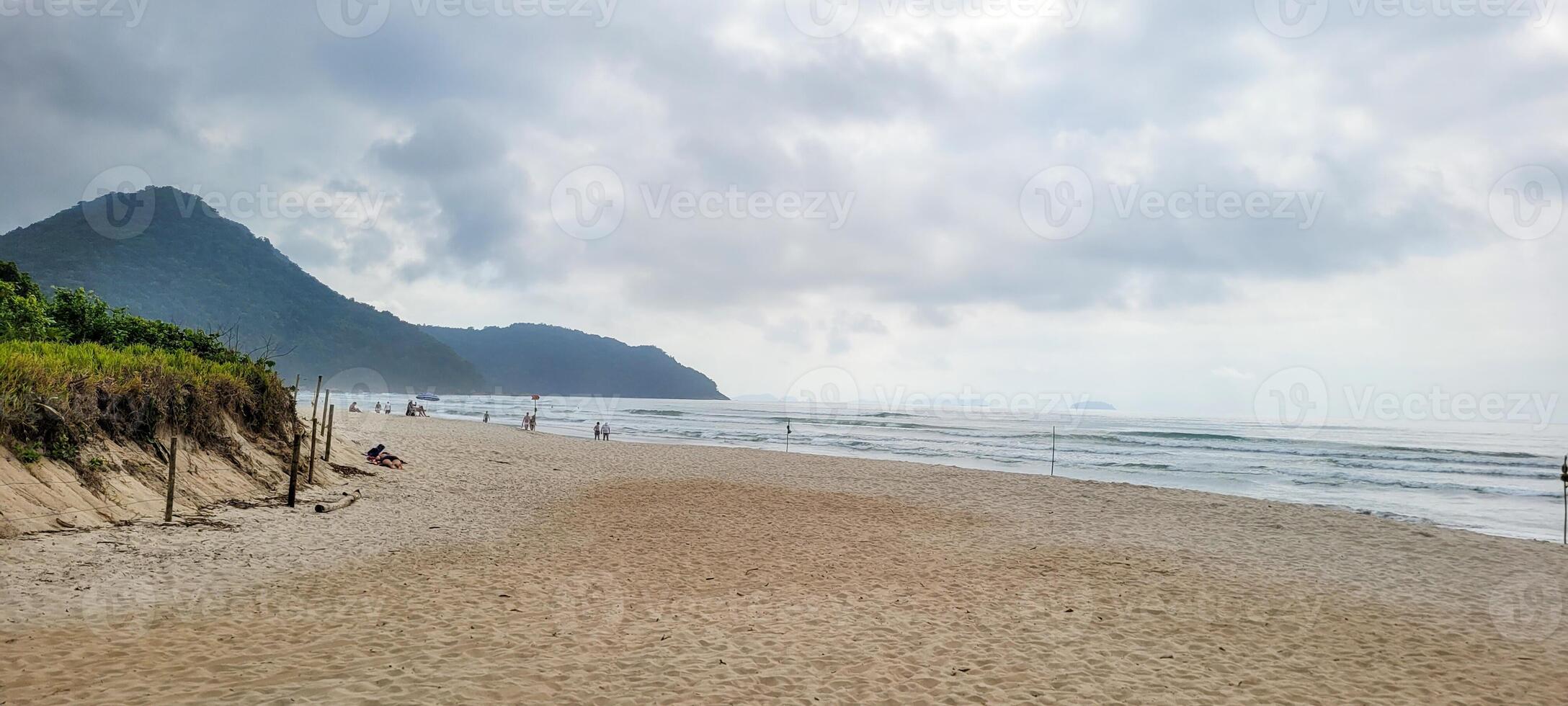 imagen de playa con blanco arena y calma mar en soleado día con bañistas y surfistas en el playa foto