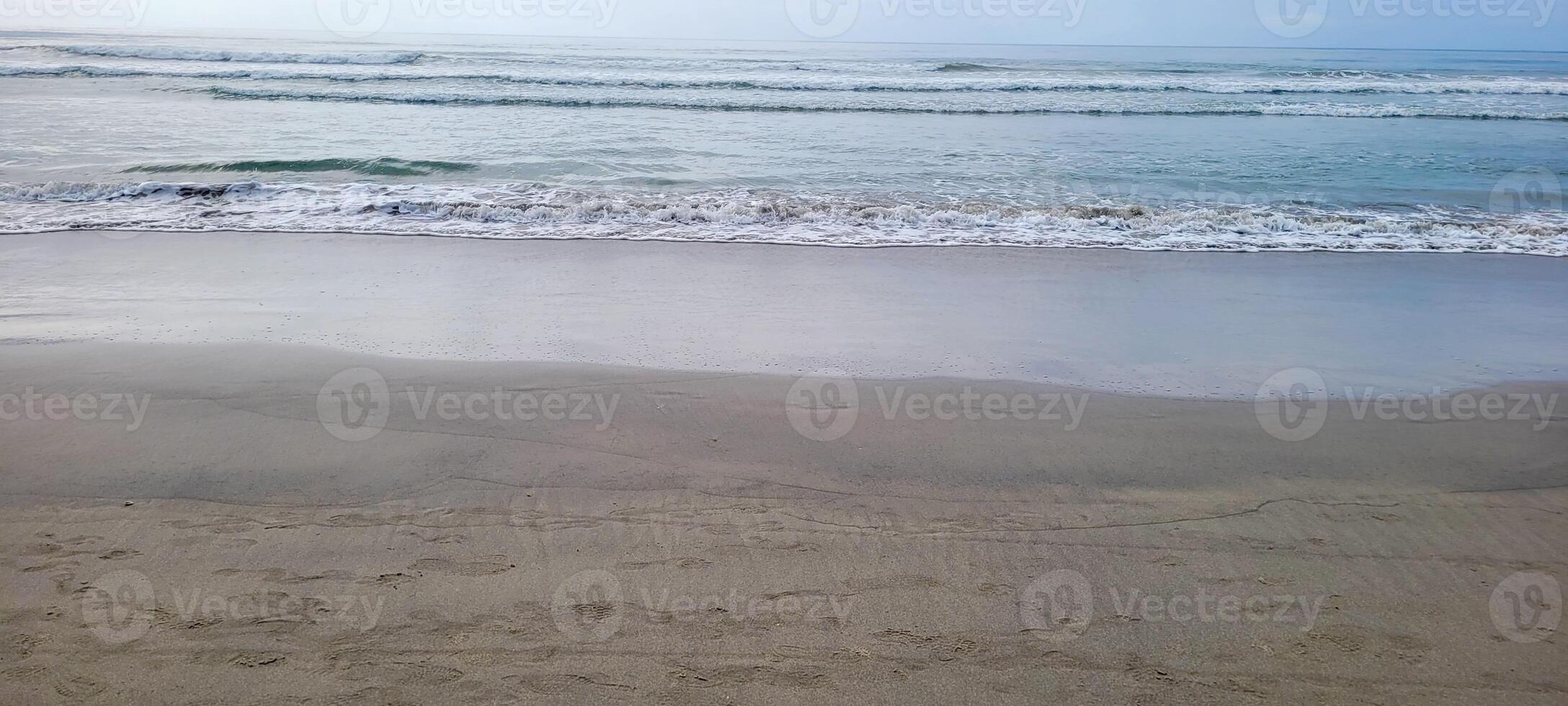 image of beach with white sand and calm sea on sunny day with bathers and surfers on the beach photo