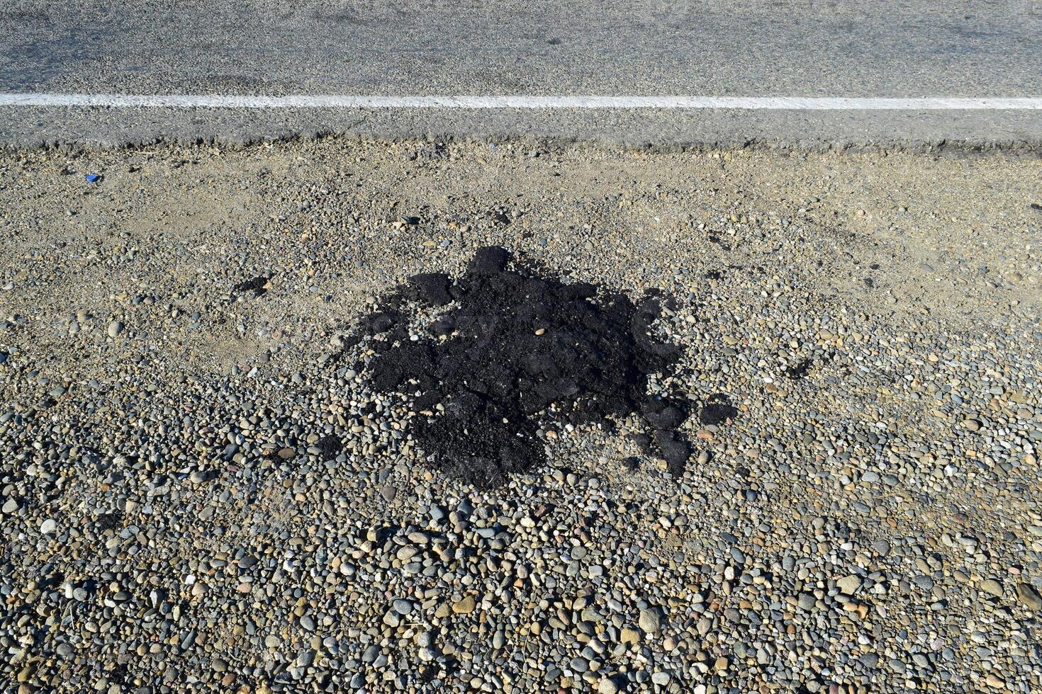 The piece of fresh asphalt which dropped out on a roadside photo