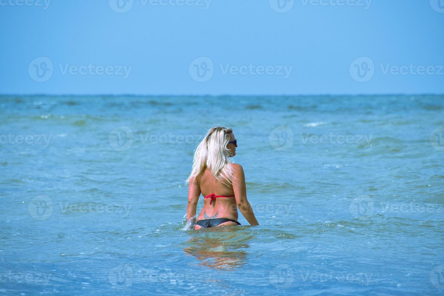 Beautiful blonde walks into the sea water photo