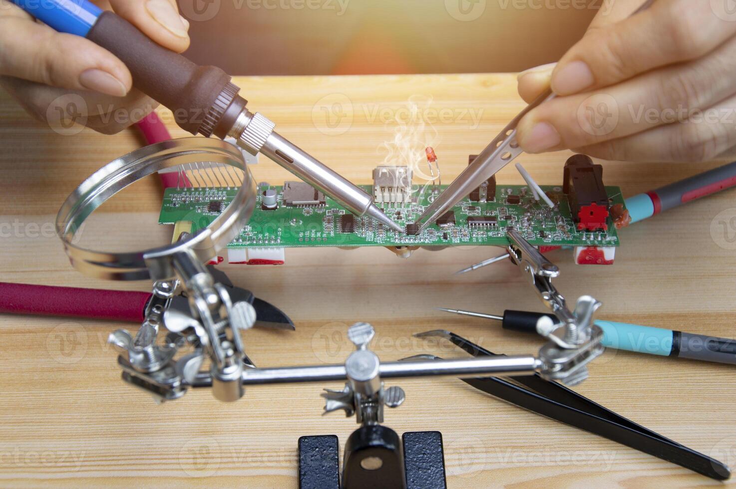 Technician is repairing motherboards and soldering equipment, repairing circuits. photo
