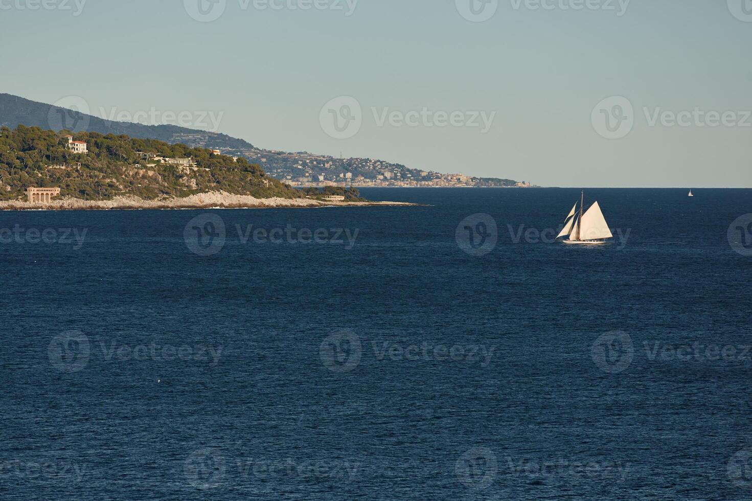 Monaco, huge sail yacht is in sea at sunset, island is nearby, wealth life of billionaires, mountains on background photo