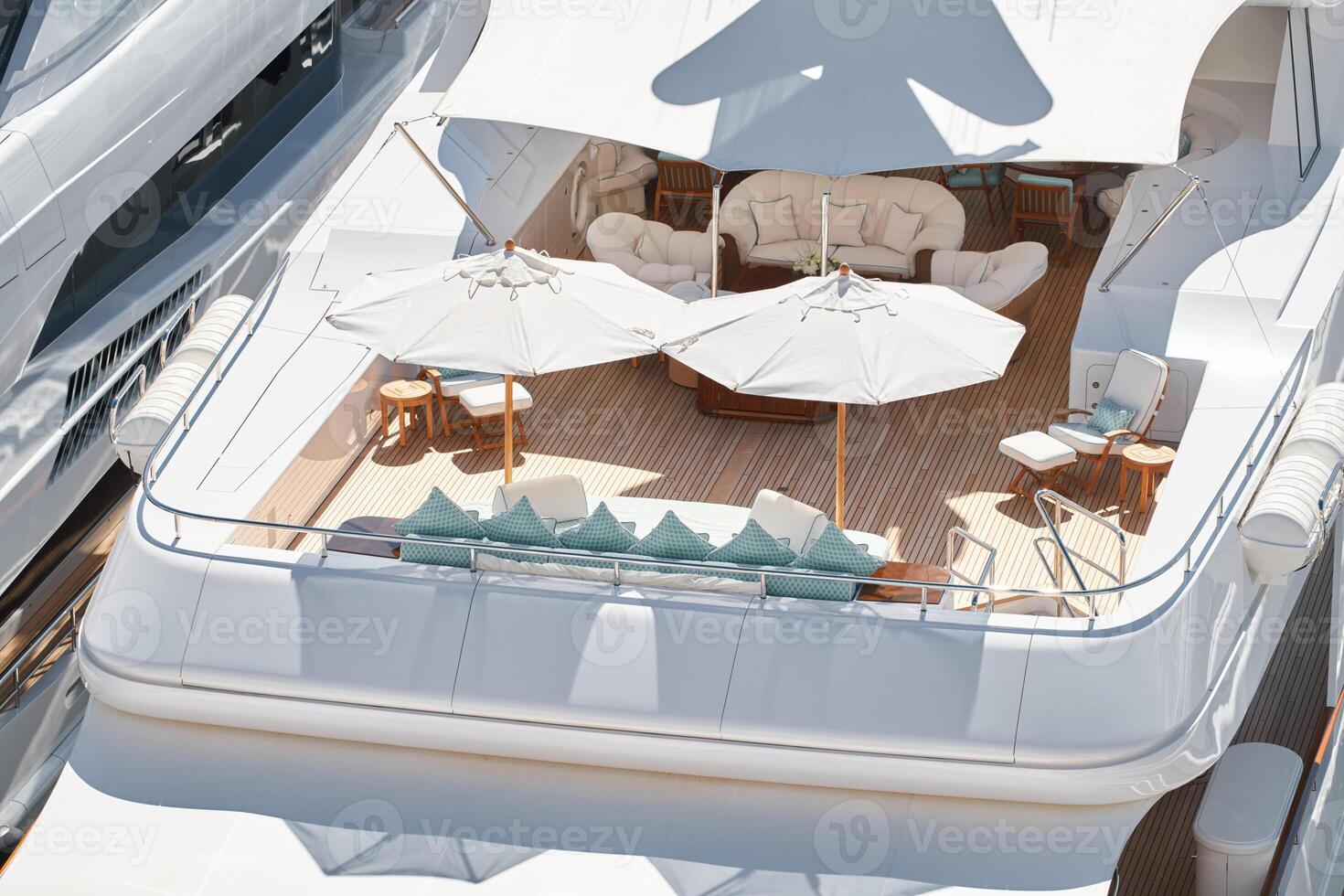 Close up footage of a relaxation area on the open teak deck of an expensive megayacht at sunny day, with awnings stretched over the deck to protect from the sun, wealth life, table and chairs photo