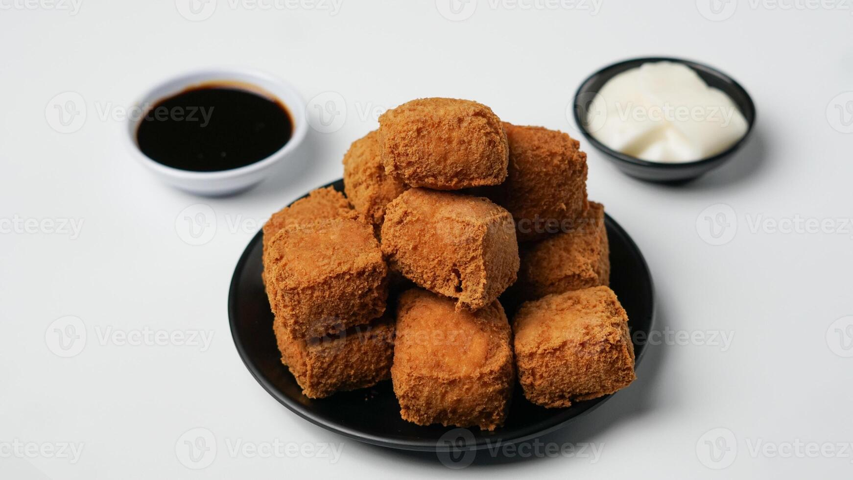 frito tofu en un negro plato con mayonesa y dulce soja salsa en un blanco antecedentes foto