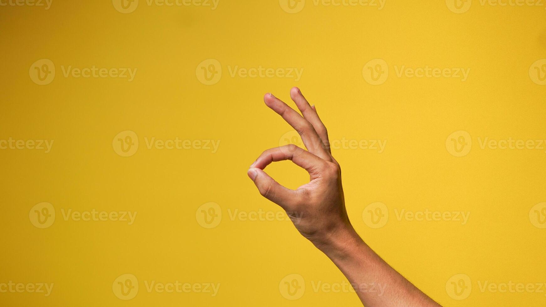 Man's hand shows okay gesture or everything is fine on a yellow background photo