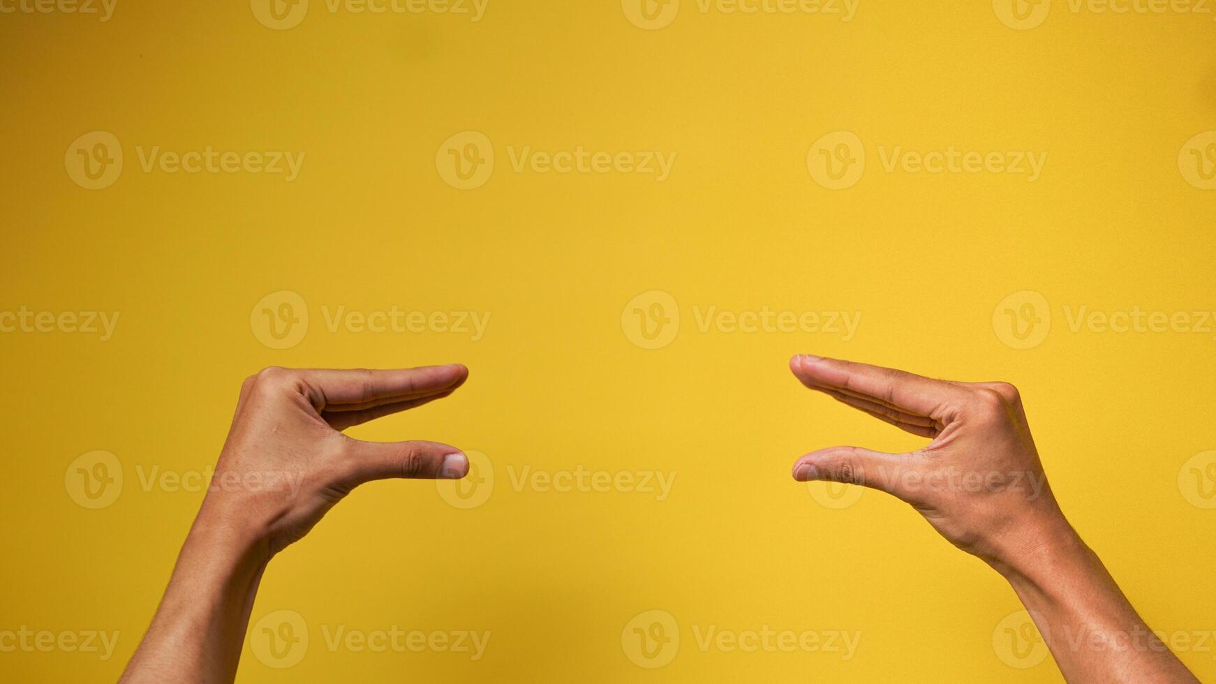 Men's hands with a gesture of two people talking on a yellow background photo