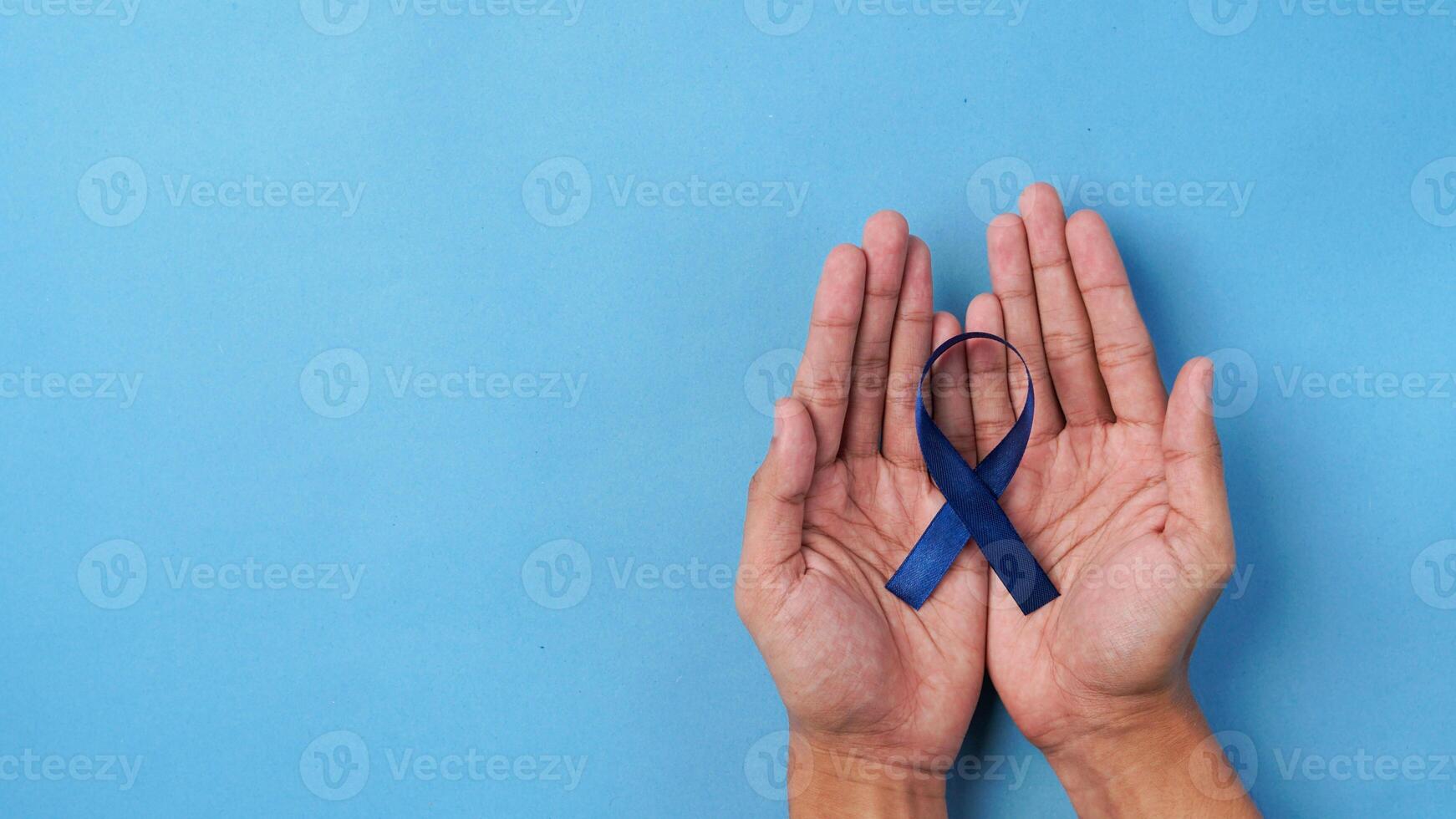 Hand holding blue ribbon on blue background. supporting world concern day photo