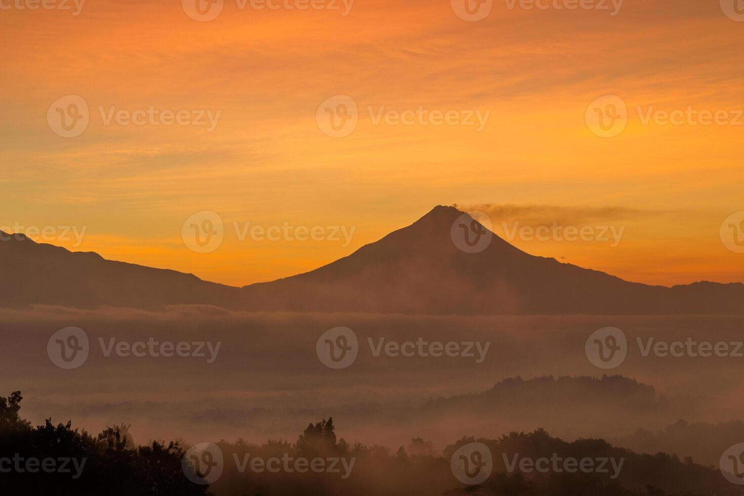 Mountain under the orange sky in the misty morning, beautiful scenery from high angle view, Indonesia photo