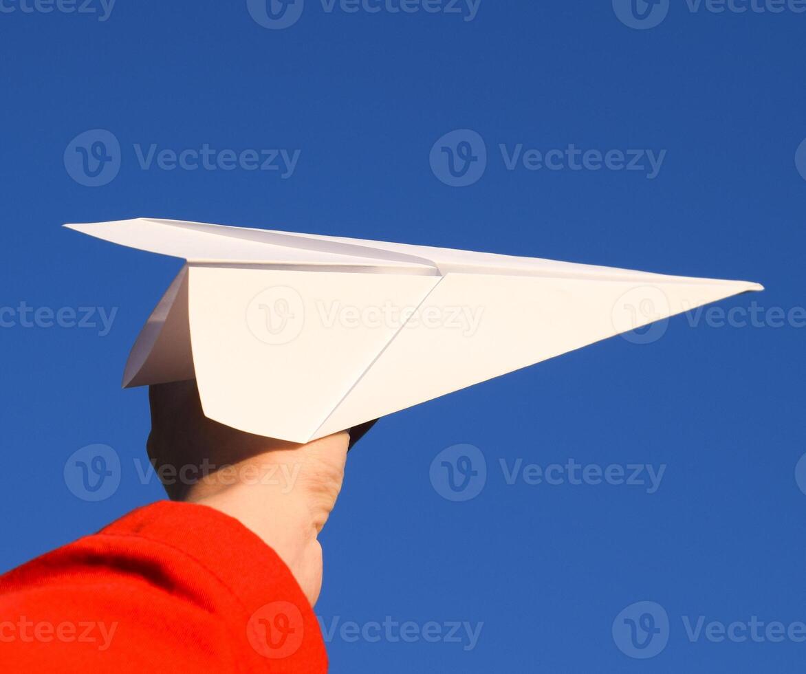 White paper airplane in hand against the sky. A symbol of freedom on the Internet photo