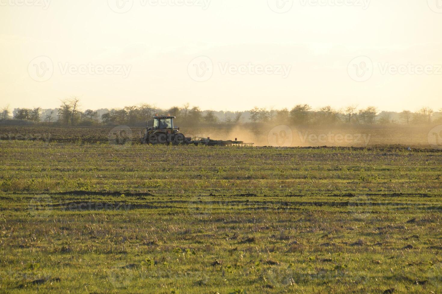 Tractor at sunset plow plow a field. Tilling the soil in the fall after harvest. The end of the season photo