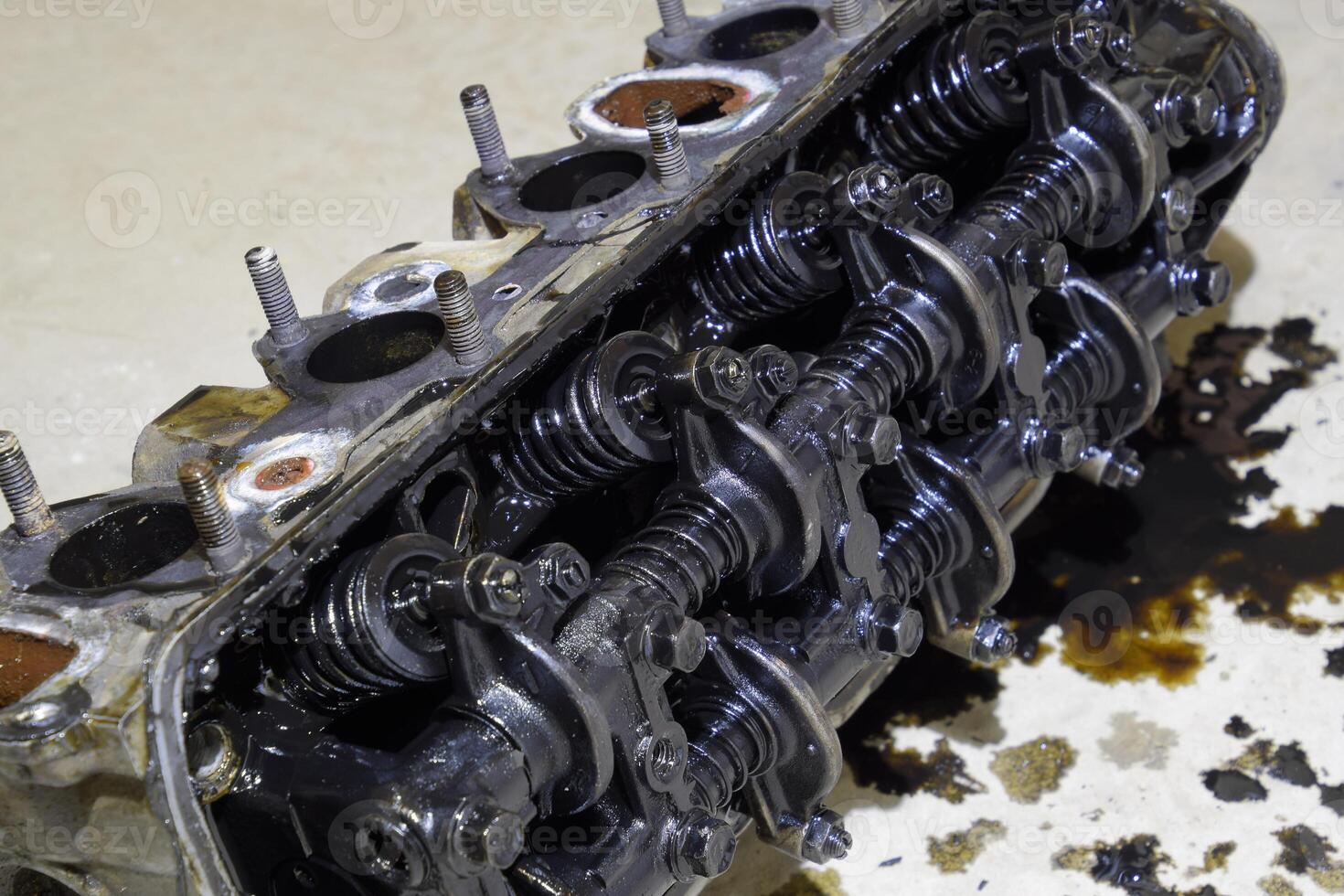 The head of the block of cylinders. The head of the block of cylinders removed from the engine for repair. Parts in engine oil. Car engine repair in the service photo