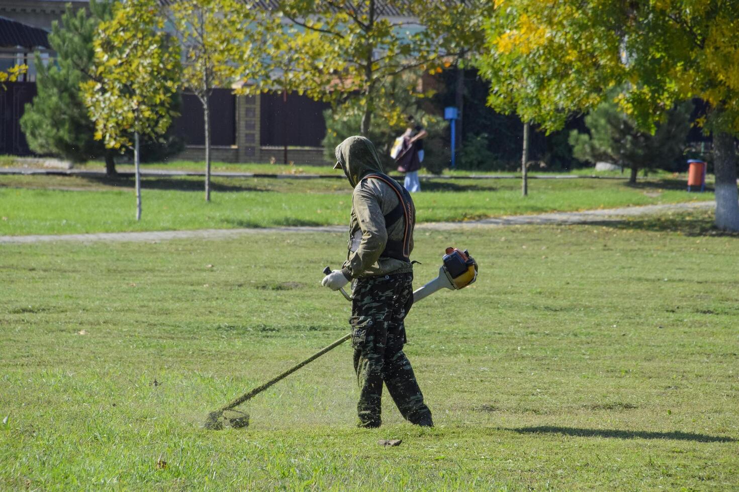 worker mowing grass with a gasoline brush. Trimmer. photo