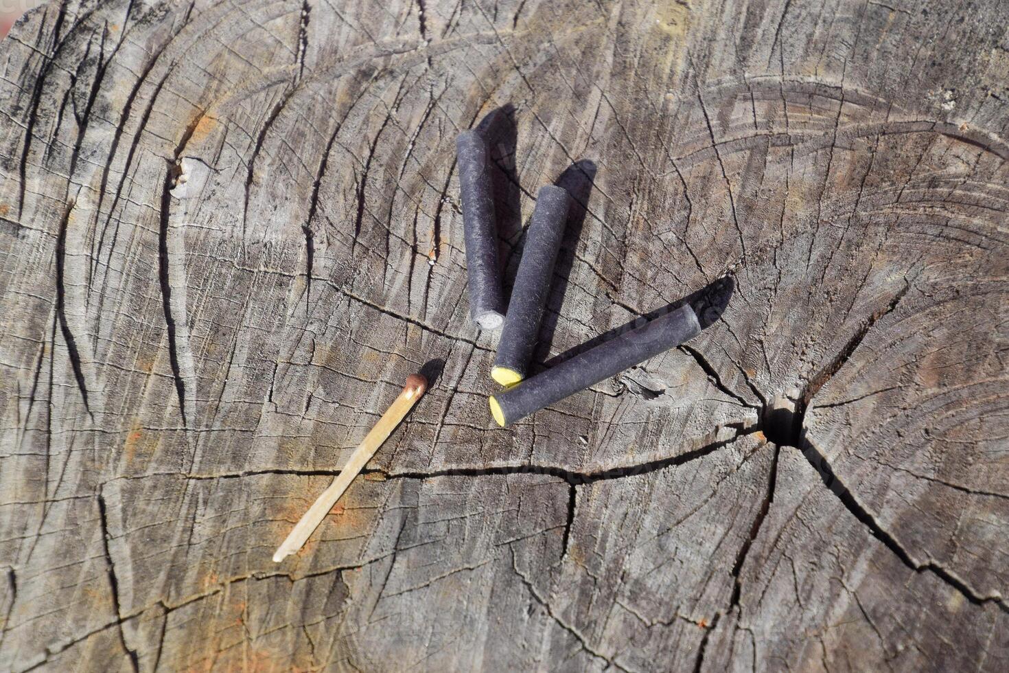 Three firecrackers and match lying on a tree stump photo