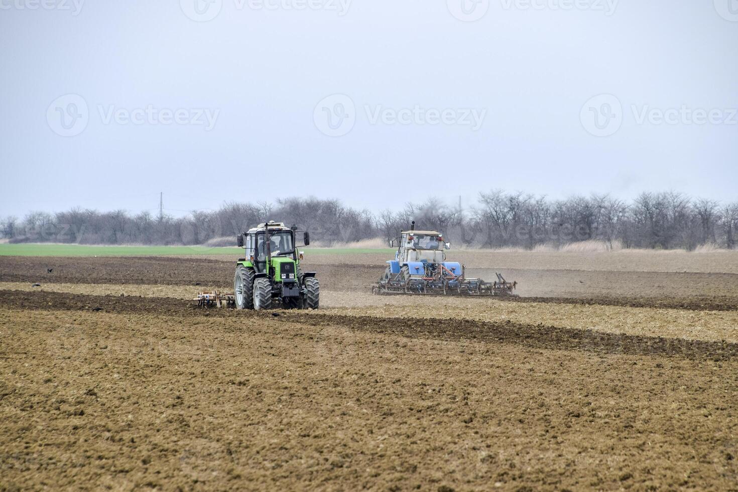Lush and loosen the soil on the field before sowing. The tractor plows a field with a plow photo