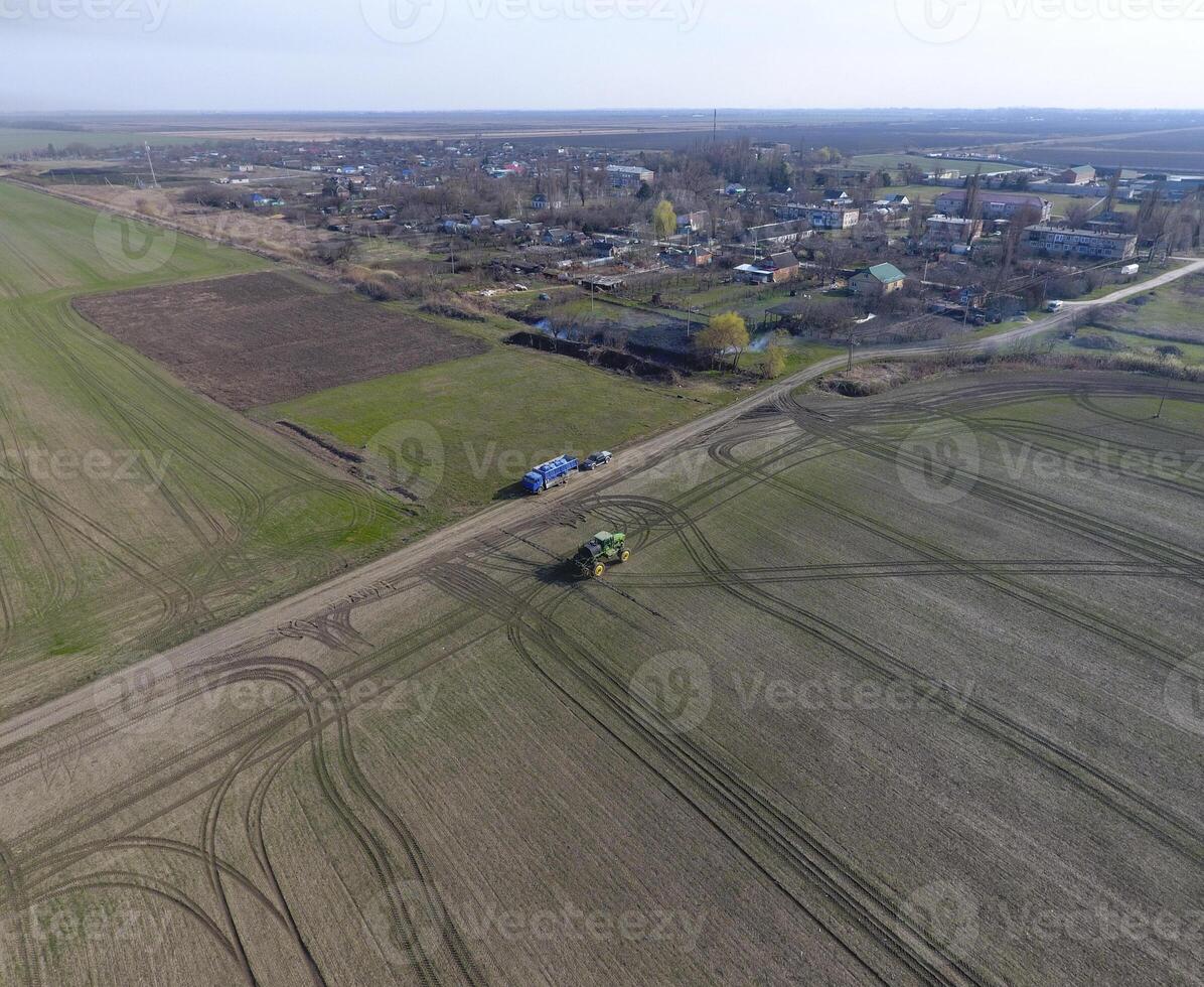 Tractor with hinged system of spraying pesticides. Fertilizing with a tractor, in the form of an aerosol, on the field of winter wheat. photo