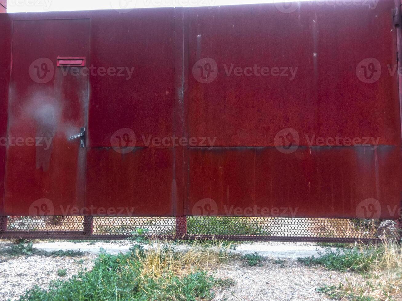 Steel rusty gates and a red brick fence. photo