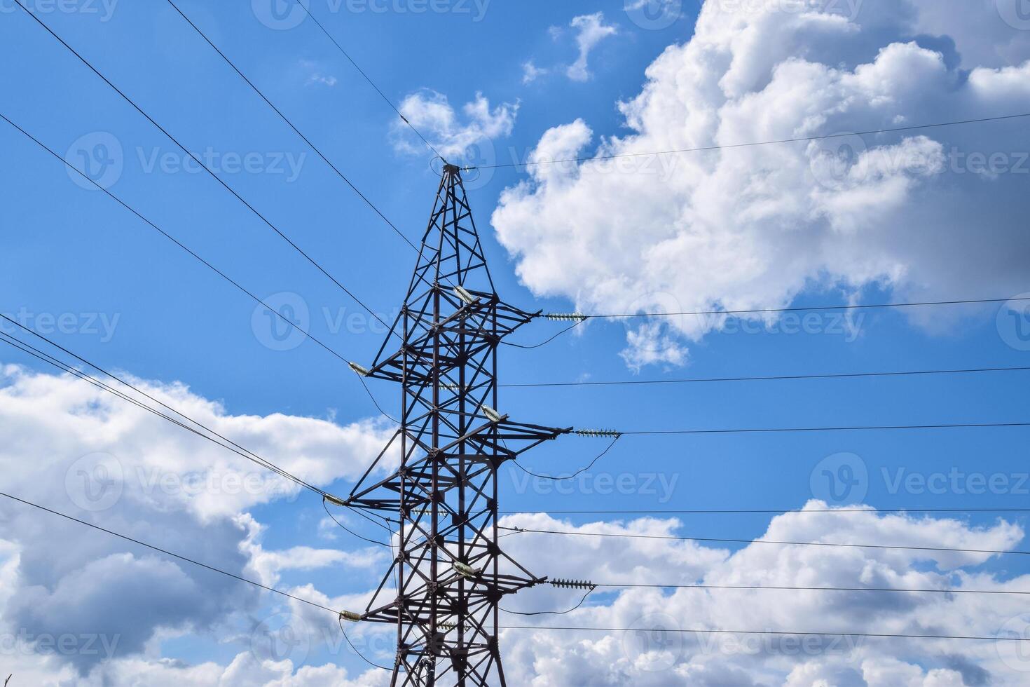 Supports high-voltage power lines against the blue sky with clouds. Electrical industry photo