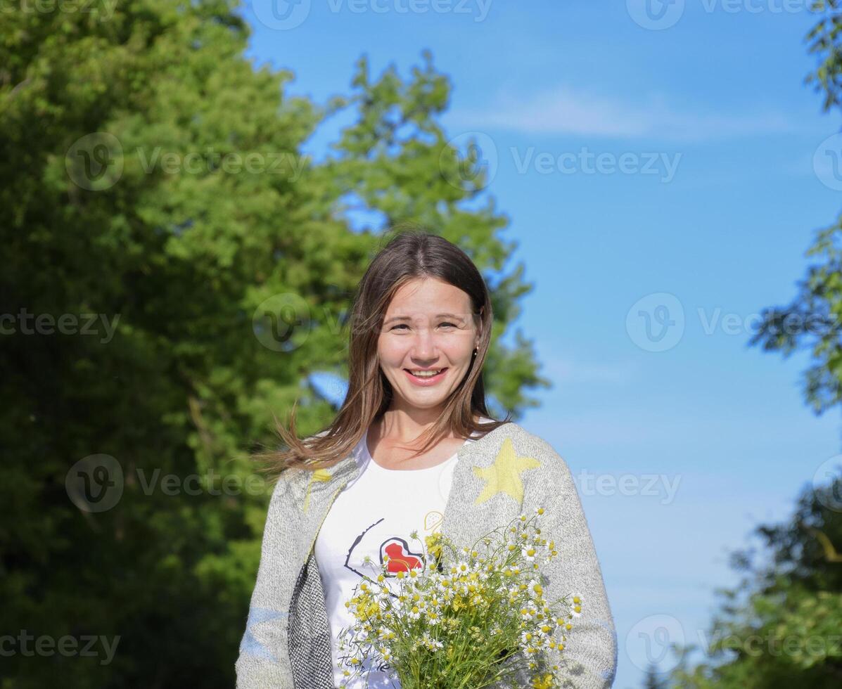joven hermosa niña con un ramo de flores de manzanilla un mujer en un cebada campo foto
