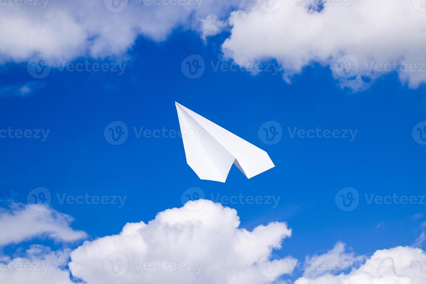 White paper airplane in a blue sky with clouds. The message symbol in the messenger photo